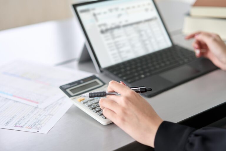 Asian,Woman,Using,Accounting,Software,And,Calculator